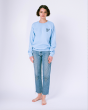 Load image into Gallery viewer, Front of light blue crewneck sweatshirt with embroidery of french bulldog face on the  left of the chest on woman in jeans
