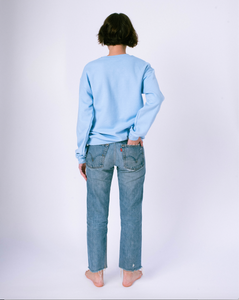 back of light blue crewneck sweatshirt on woman in jeans