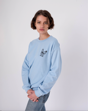 Load image into Gallery viewer, Side view of light blue crewneck sweatshirt with embroidery of french bulldog face on the  left of the chest on woman in jeans
