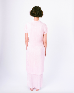 Back of pink pleated tiered maxi dress with mock neck and short sleeves on woman