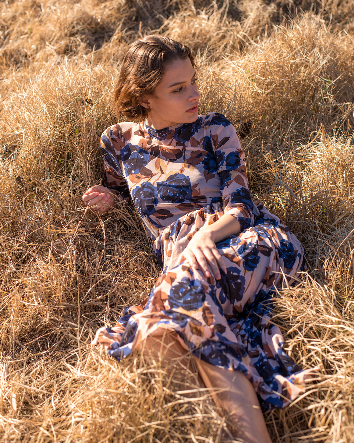Blue floral print on tan mesh overlay a-line dress with long sleeves over slip dress on woman
