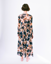 Load image into Gallery viewer, Back view of blue floral print on tan mesh overlay a-line dress with long sleeves over slip dress on woman
