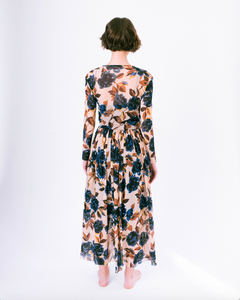 Back view of blue floral print on tan mesh overlay a-line dress with long sleeves over slip dress on woman