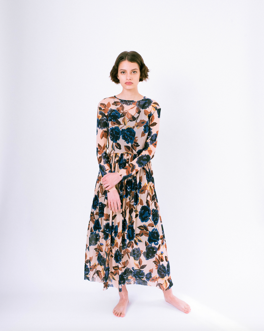 Front view of blue floral print on tan mesh overlay a-line dress with long sleeves over slip dress on woman