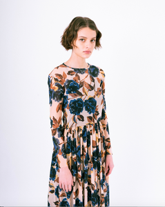 Side profile view of blue floral print on tan mesh overlay a-line dress with long sleeves over slip dress on woman