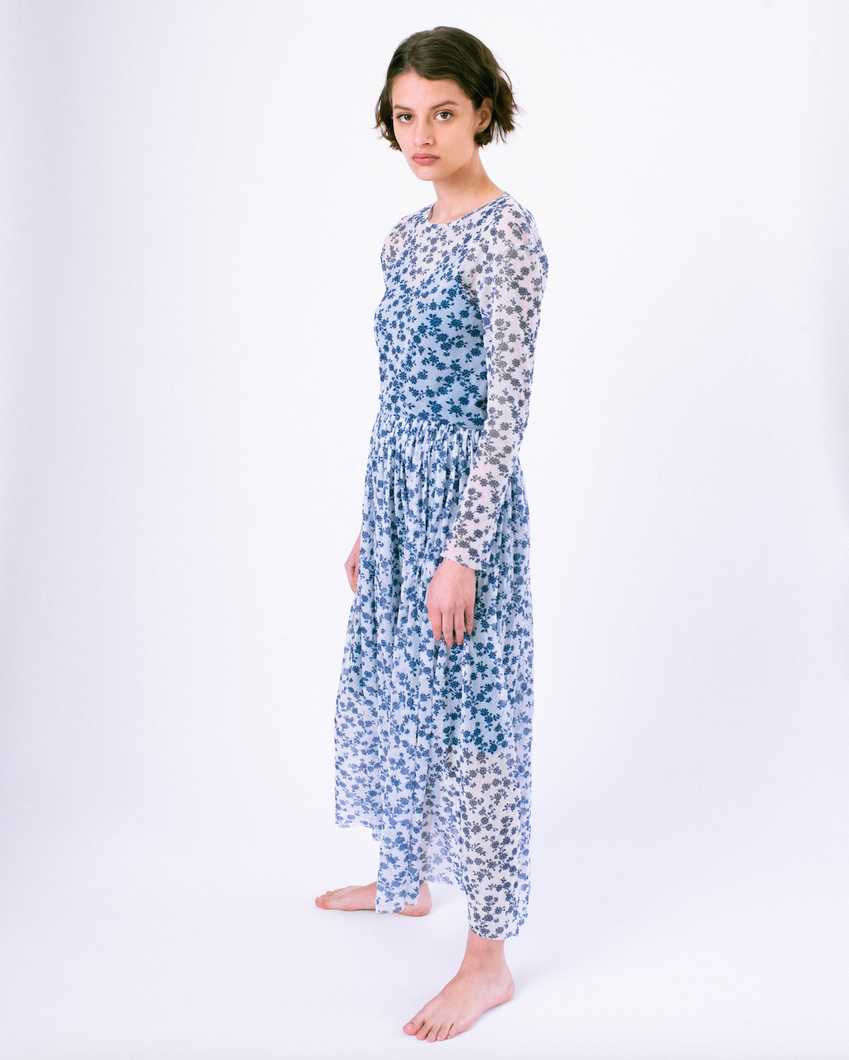 Side profile view of long sleeve blue and white floral a-line dress with mesh overlay over slip dress on woman