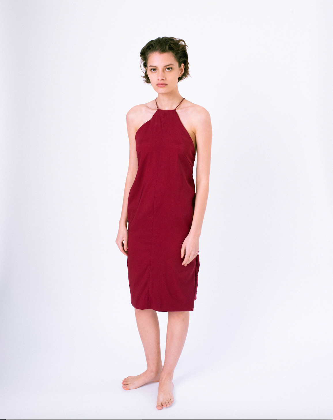 Front of dark red halter dress with open back & crossed straps on woman