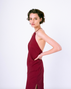 Side profile of dark red halter dress with open back & crossed straps on woman